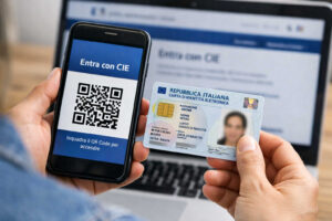 Come passare da SPID a CIE per accedere ai servizi della Pubblica Amministrazione Un cittadino mantiene uno smartphone in una mano e una carta d'identità elettronica CiE nell'altra mano, mentre è seduto ad un computer.